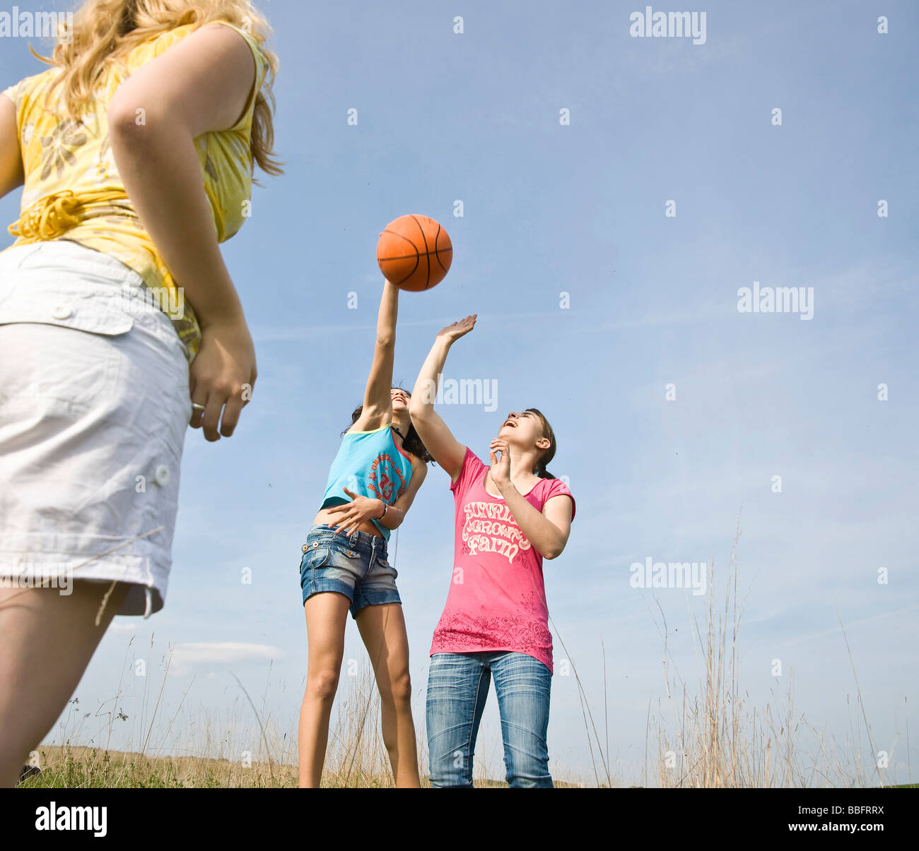 Le tre ragazze a giocare con una palla da basket su un prato Foto Stock