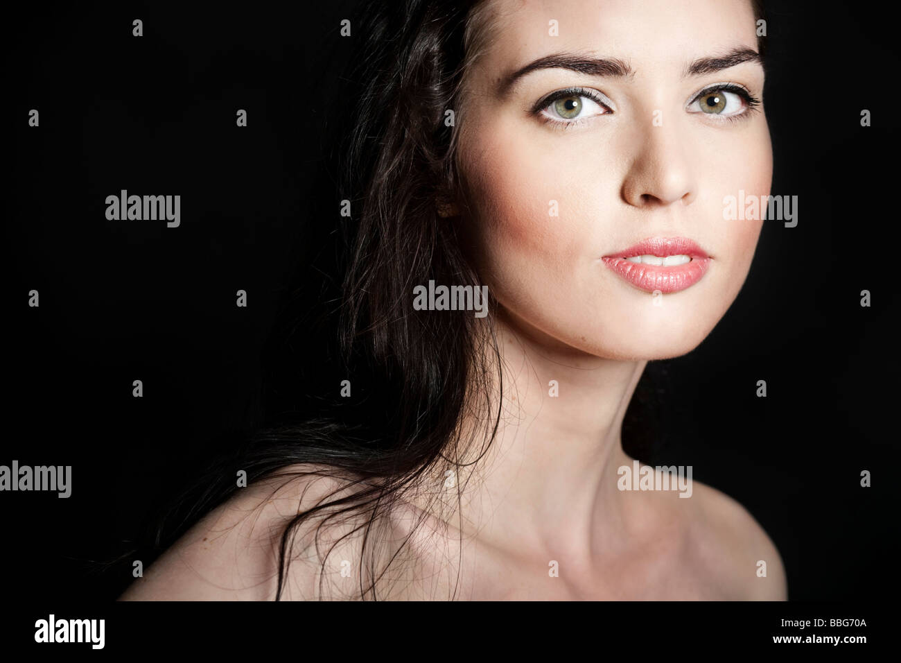 Ritratto di una giovane dai capelli scuri donna di fronte a uno sfondo nero Foto Stock