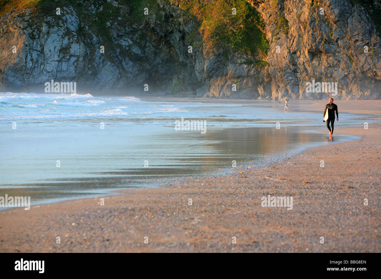 Surfer passeggiate lungo la spiaggia di Holywell, vicino a Newquay, Cornwall, Regno Unito Foto Stock