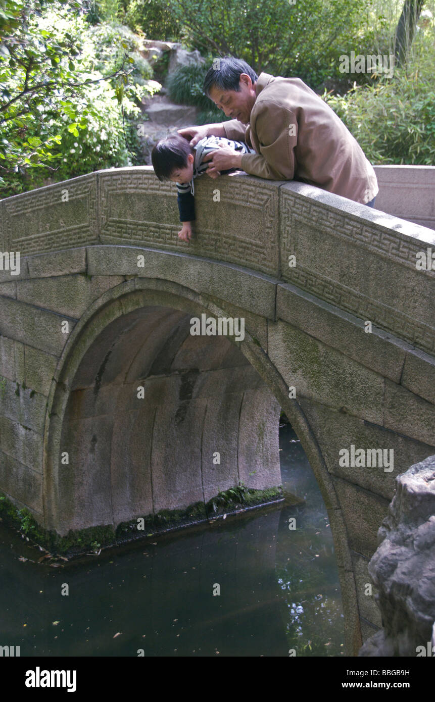 Uomo e bambino sul ponte di pietra guardando goldfish umile amministratore s Garden Suzhou Jiansu Cina Foto Stock