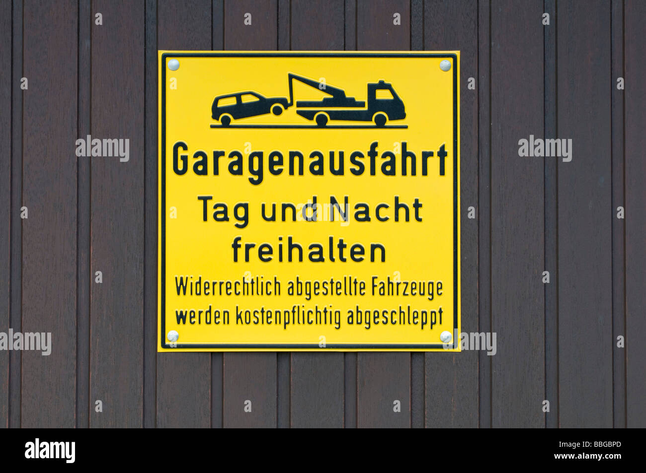 Cartello giallo sulla porta del garage, mantenere la uscita di garage accessibile di giorno e di notte, illegalmente parcheggiato veicoli dovranno essere trainato con costi Foto Stock