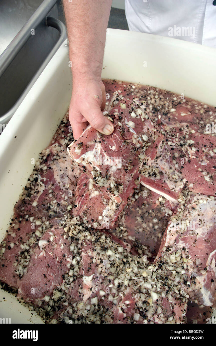 La rimozione di acqua salata e di carne di maiale che è stata coperta con le cipolle e le bacche di ginepro dall'indurimento pot, produzione di bava Foto Stock