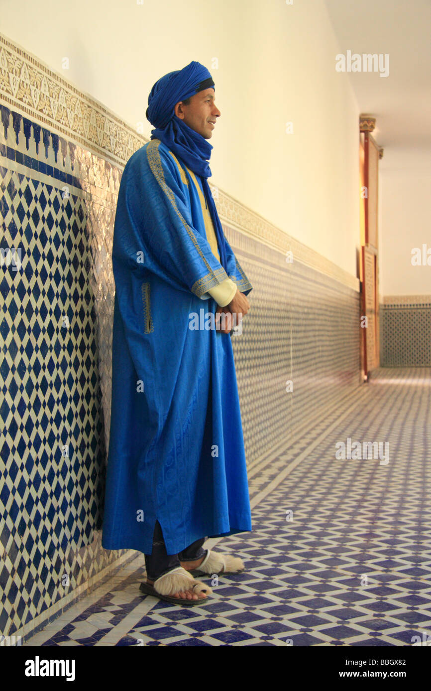 Uomo marocchino nel tradizionale blu accappatoi/camice da design Islamico pareti piastrellate (zellij), Mausoleo di Ali Cherif, Rissani,Marocco Foto Stock