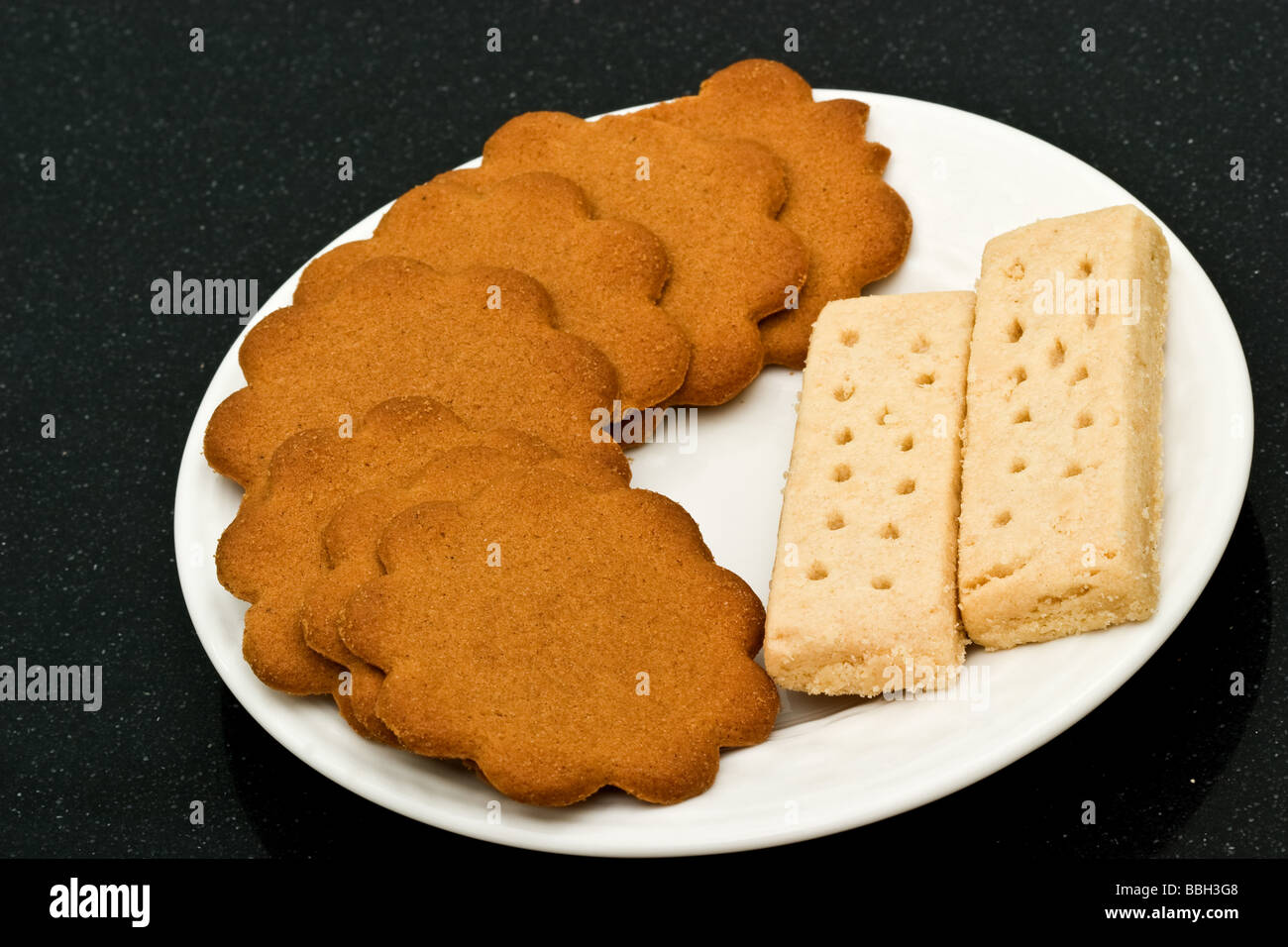 Due biscotti frollini dita con lo zenzero scatta su una piastra bianca Foto Stock