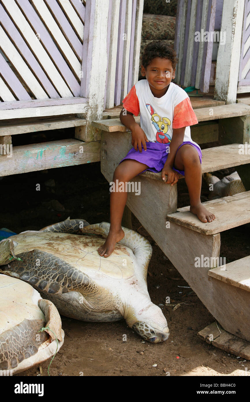 Tasbapauni, Nicaragua; ragazzo giovane con il suo piede su una tartaruga di mare Foto Stock