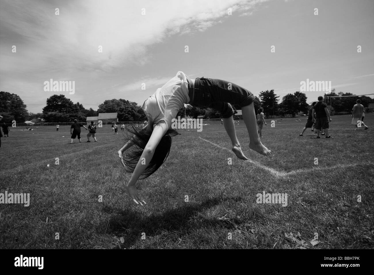Una ragazza adolescente fa un backflip su un campo durante l'incavo alla sua High School nel Connecticut USA Foto Stock
