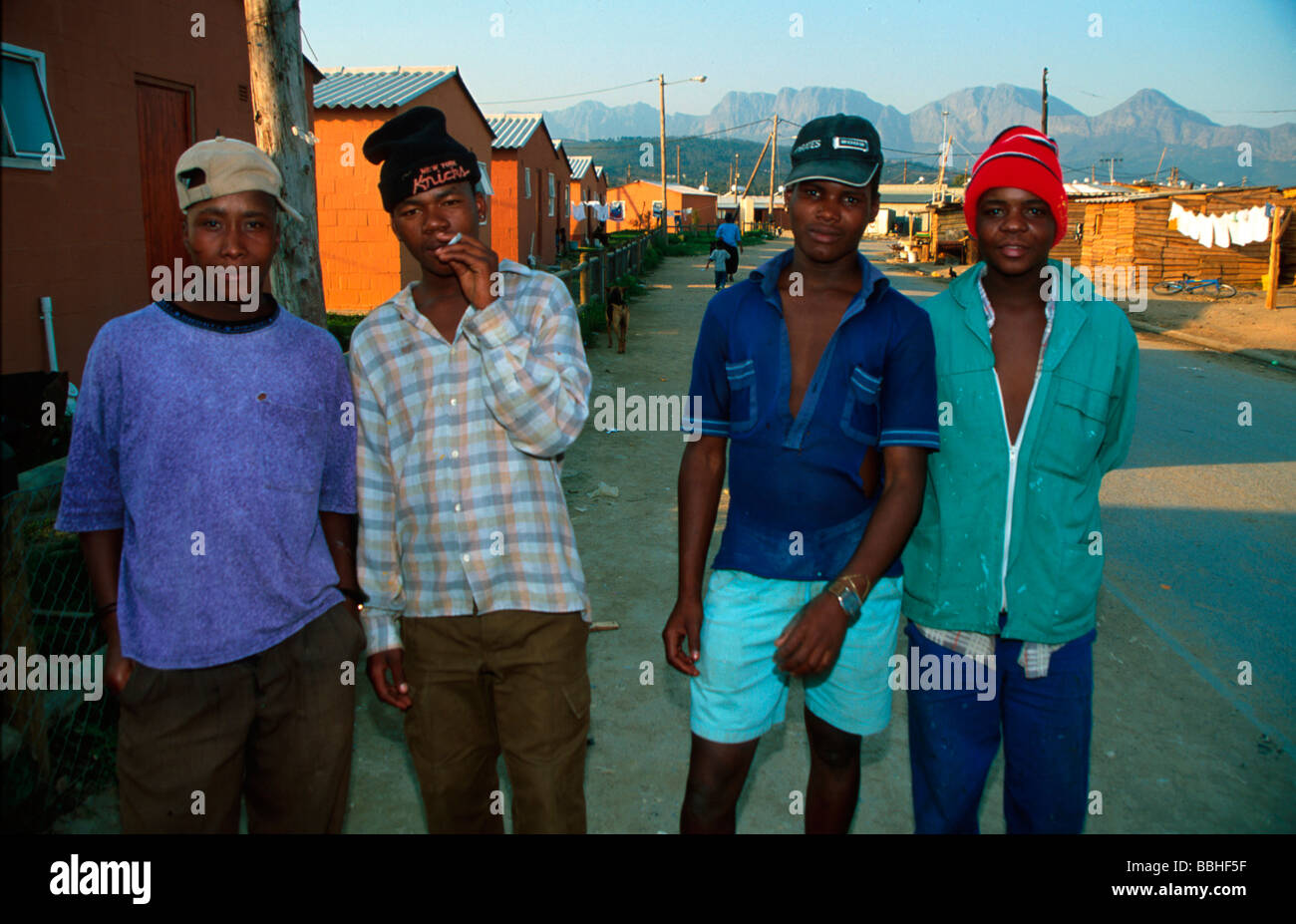 Giovani uomini passeggiare tra piazza Fatyela giovani uomini nelle township del Western Cape hanno spesso difficoltà a trovare posti di lavoro e Foto Stock