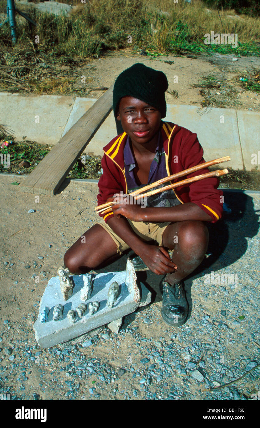Al Nkomati river bridge Sibusiso Twala mostra fuori le sue sculture in pietra ollare Egli mantiene il tamburo bastoni in una sola mano che egli utilizza per Foto Stock