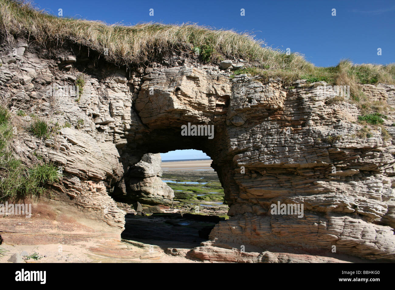 Wave-Cut arco in pietra arenaria Bunter su Hilbre Island, il Wirral, Merseyside, Regno Unito Foto Stock