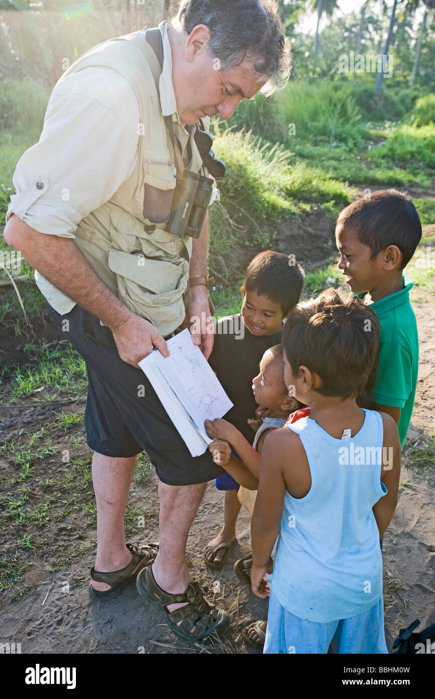 Tim Appleton mostra ragazzi illustrazioni di uccelli in una guida di campo a Narra su PALAWAN FILIPPINE Foto Stock