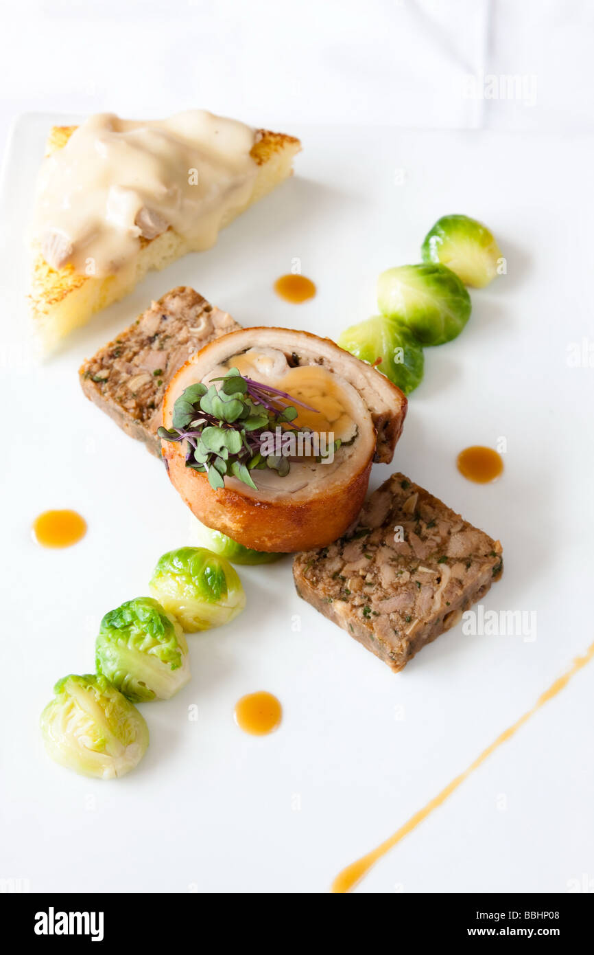 Naso di coda di maiale servito con cuit sous vide il prosciutto di lombo di Welsh rarebit brawn fritto i cavoletti di Bruxelles e Arancio sanguigno jus Foto Stock