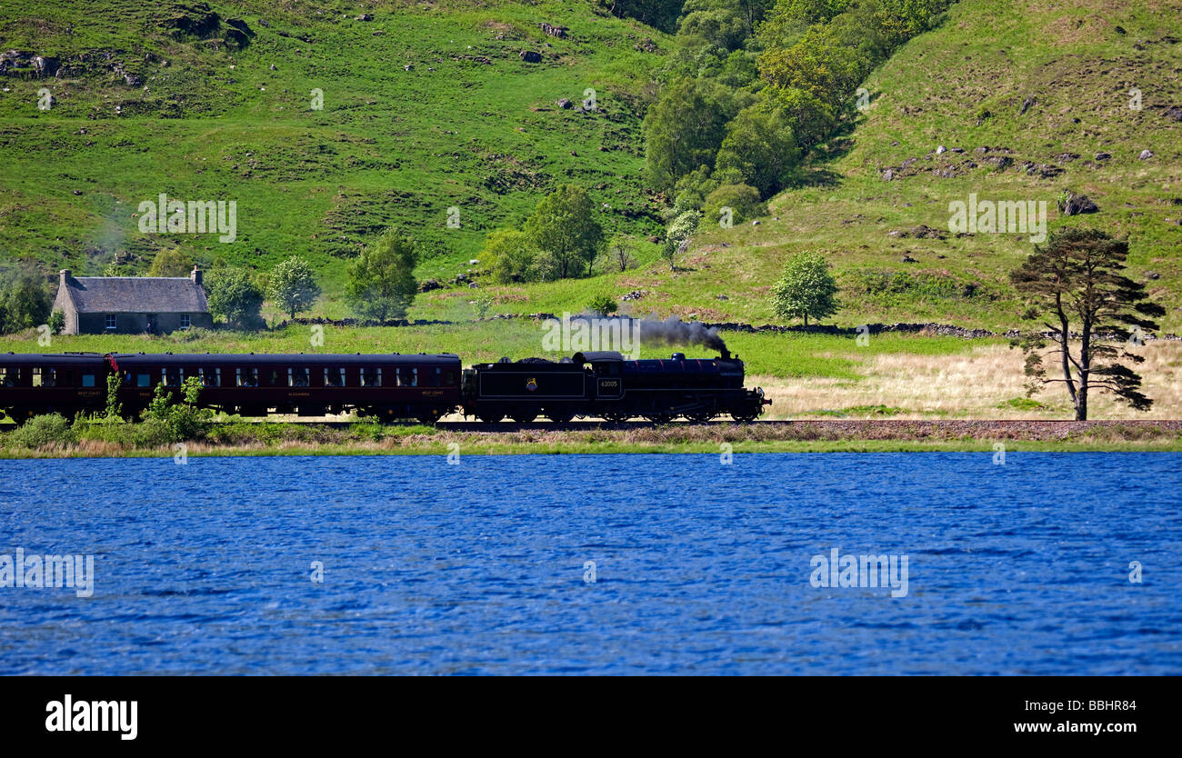 Giacobita treno a vapore con il Loch Eilt in primo piano, Lochaber, Scotland, Regno Unito, Europa Foto Stock