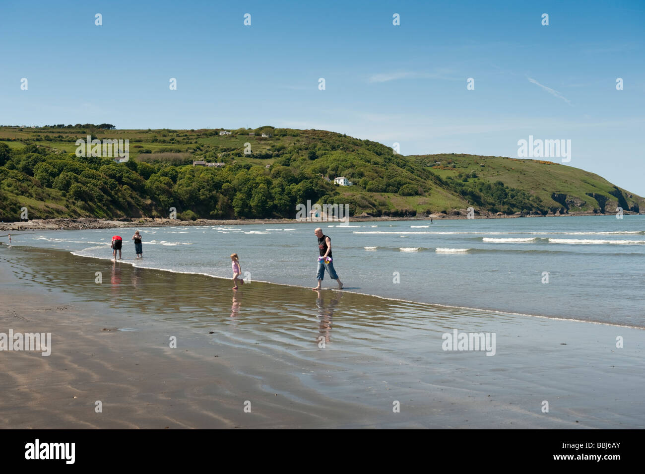 Persone sguazzare nel mare in un caldo pomeriggio estivo Poppit Sands Beach Parco Nazionale di Pembrokeshire Wales UK Foto Stock