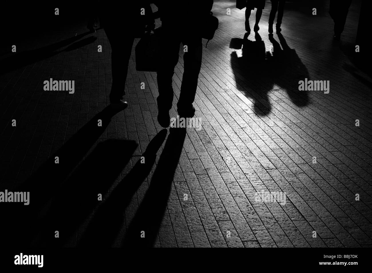 I contorni e le ombre dei pedoni a piedi nella tarda sera del sole lungo il Tamigi percorso, città di Londra, Regno Unito Foto Stock