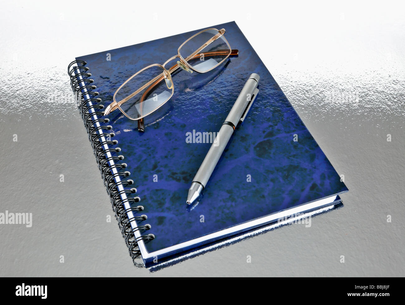 Rilegato a spirale blue note book con gli occhiali e penna Foto Stock