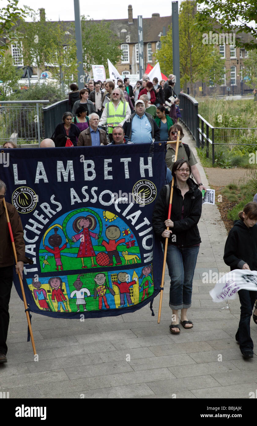 Manifestanti marciano attraverso giardini Cornmill, attraverso il fiume Ravensbourne, infront di Lewisham Ponte Scuola primaria Foto Stock