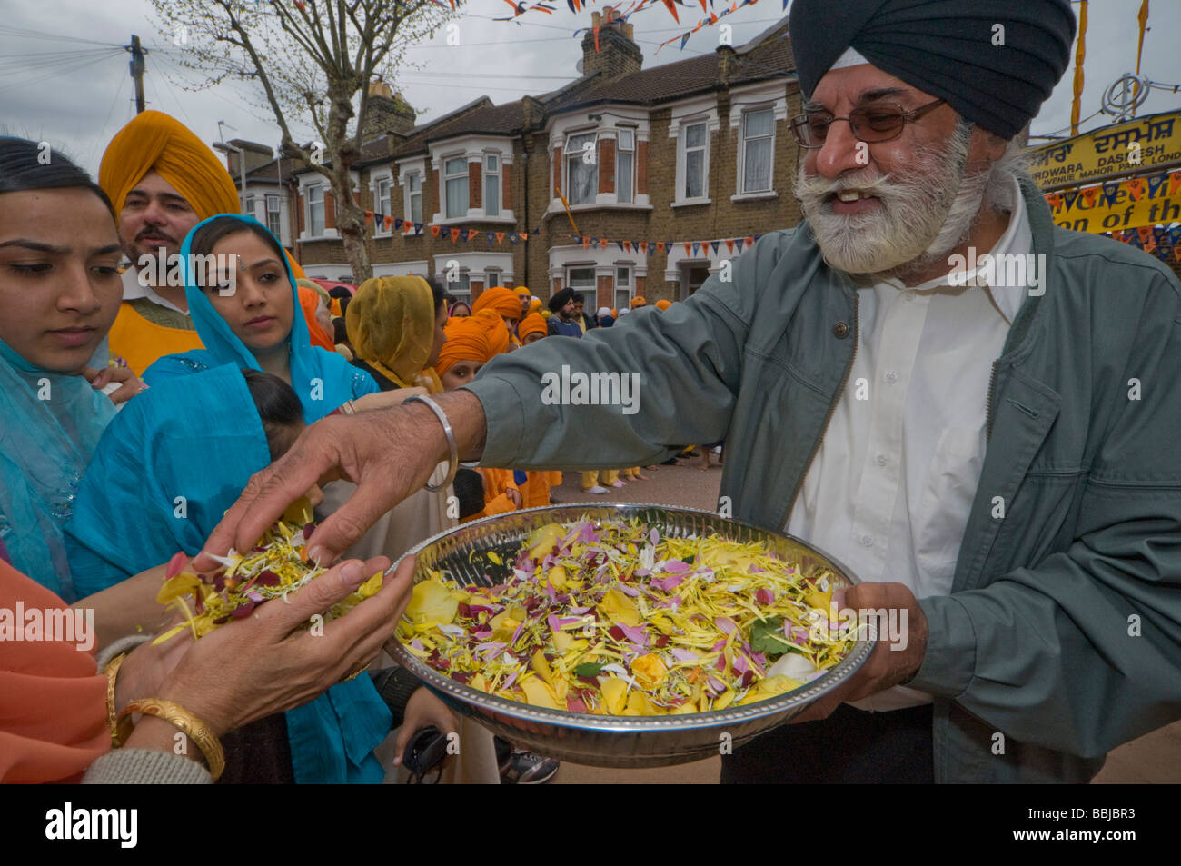 Distribuendo petali di fiori per gettare sul Guru Granth Sahib. Vaisakhi processione in Manor Park, Londra. Foto Stock