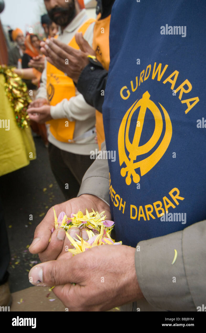 Le persone in attesa di petali di fiori pronti a gettare quando il Guru Granth Sahib viene portato fuori. Vaisakhi processione in Manor Park, Londra. Foto Stock