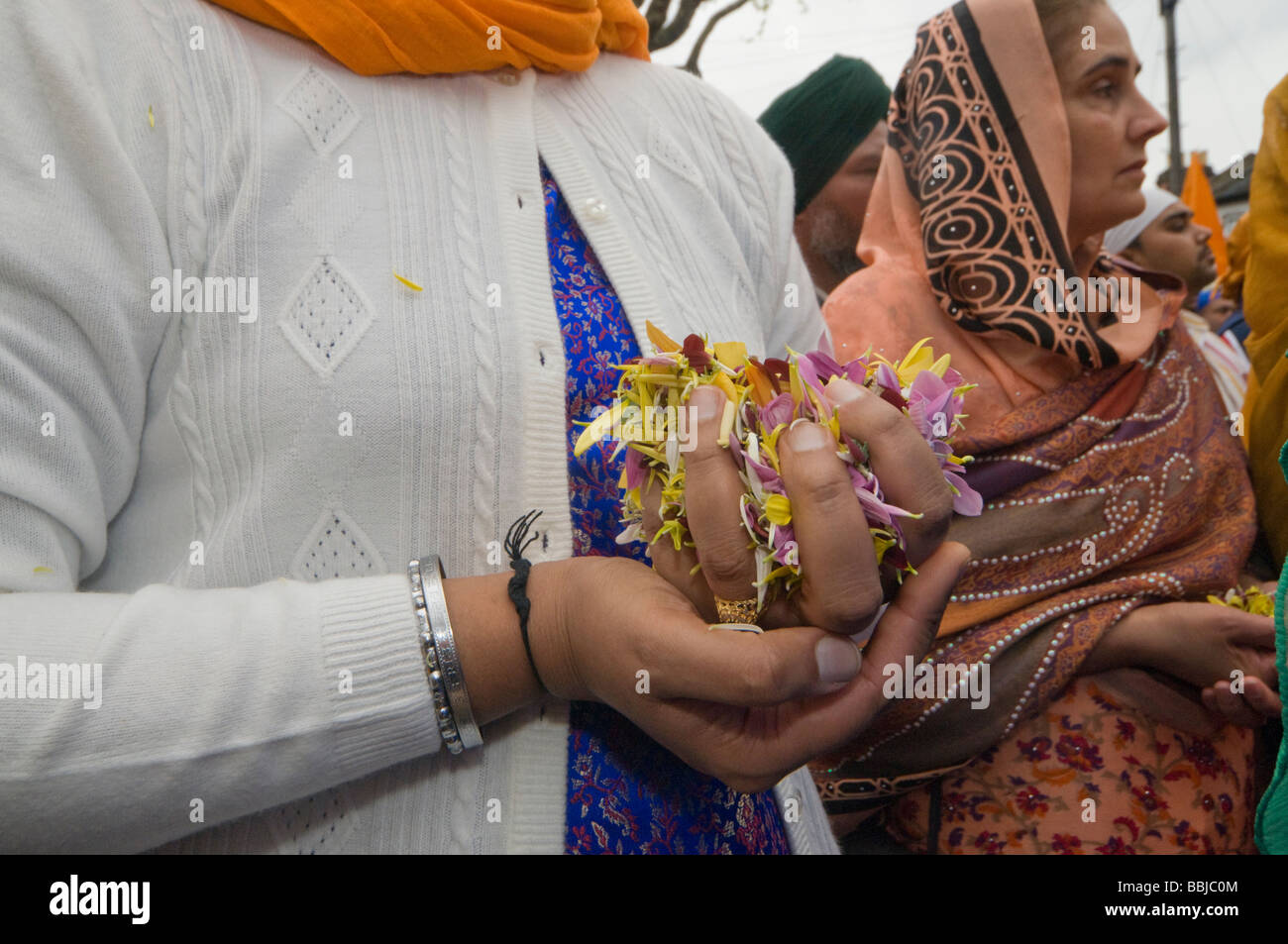 Le donne in attesa di petali di fiori pronti a gettare quando il Guru Granth Sahib viene portato fuori. Vaisakhi processione in Manor Park, Londra. Foto Stock