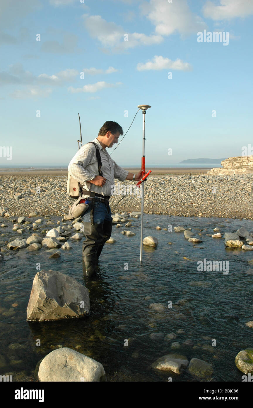 Idrologia tecnico impresa fiume misurazioni a un piccolo fiume che entra in mare nel Galles del Nord Regno Unito Foto Stock