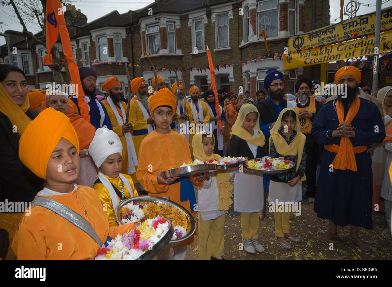 Giovane sikh portano ghirlande di fiori in vassoi al di fuori della Gurdwara per il Vaisakhi processione in Manor Park, Londra. Foto Stock