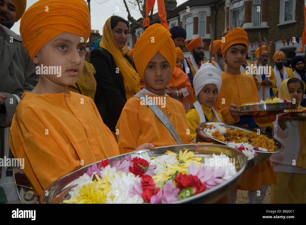 I giovani portano i sikh vassoi con ghirlande di fiori per la Panj Piare; Vaisakhi processione in Manor Park, Londra. Foto Stock
