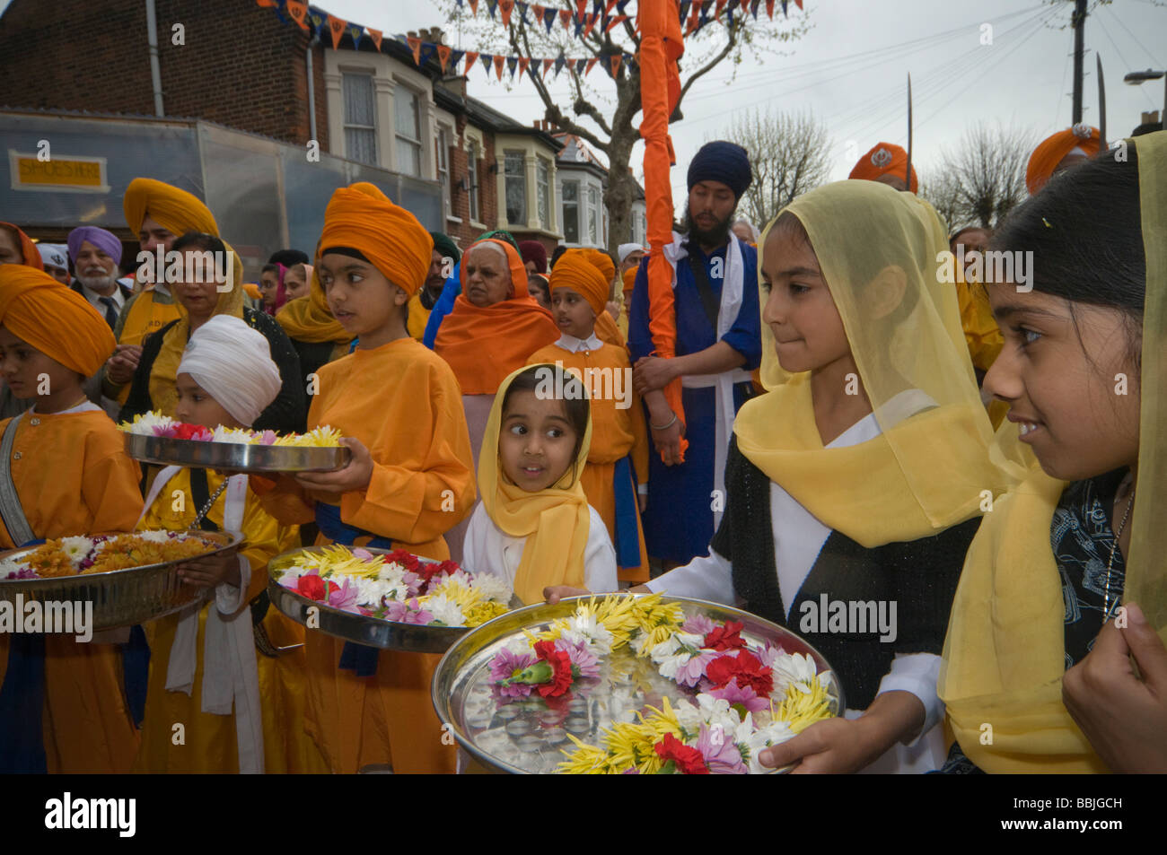 Giovane sikh portano ghirlande di fiori in vassoi al di fuori della Gurdwara per il Vaisakhi processione in Manor Park, Londra. Foto Stock