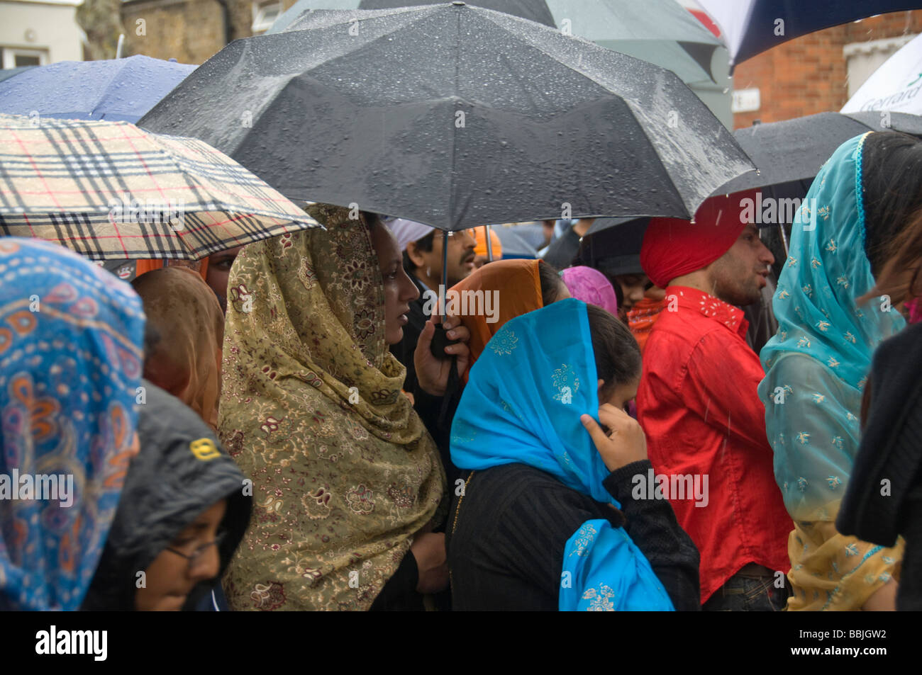 I sikh tenere gli ombrelli come piove pesantemente sul Vaisakhi processione in Manor Park, Londra. Foto Stock