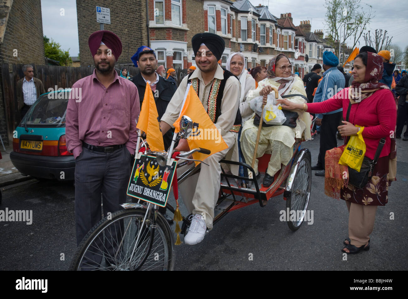 In rickshaw in bicicletta e a piedi i sikh Vaisakhi in processione in Manor Park, Londra. Foto Stock