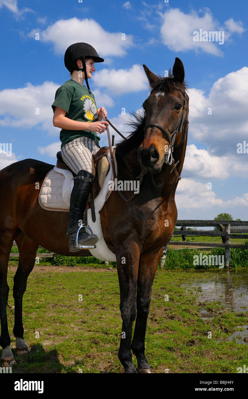 Ragazza adolescente in appoggio il suo cavallo purosangue in un recinto dopo un sentiero di marcia ontario Foto Stock