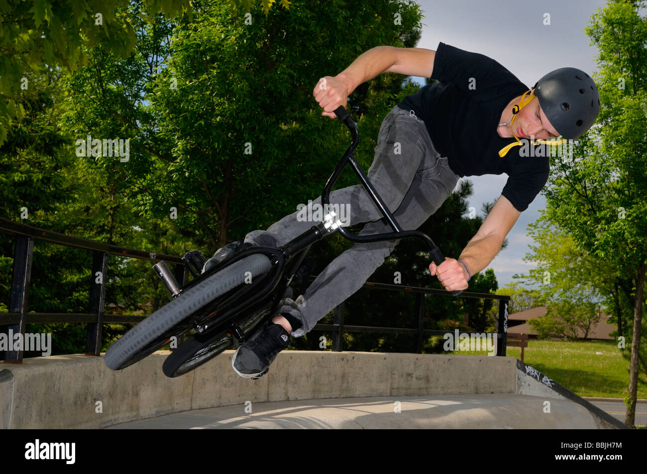 BMX bike rider battenti fuori da un muro di cemento prendere l'aria in un ambiente urbano skatepark Toronto Foto Stock