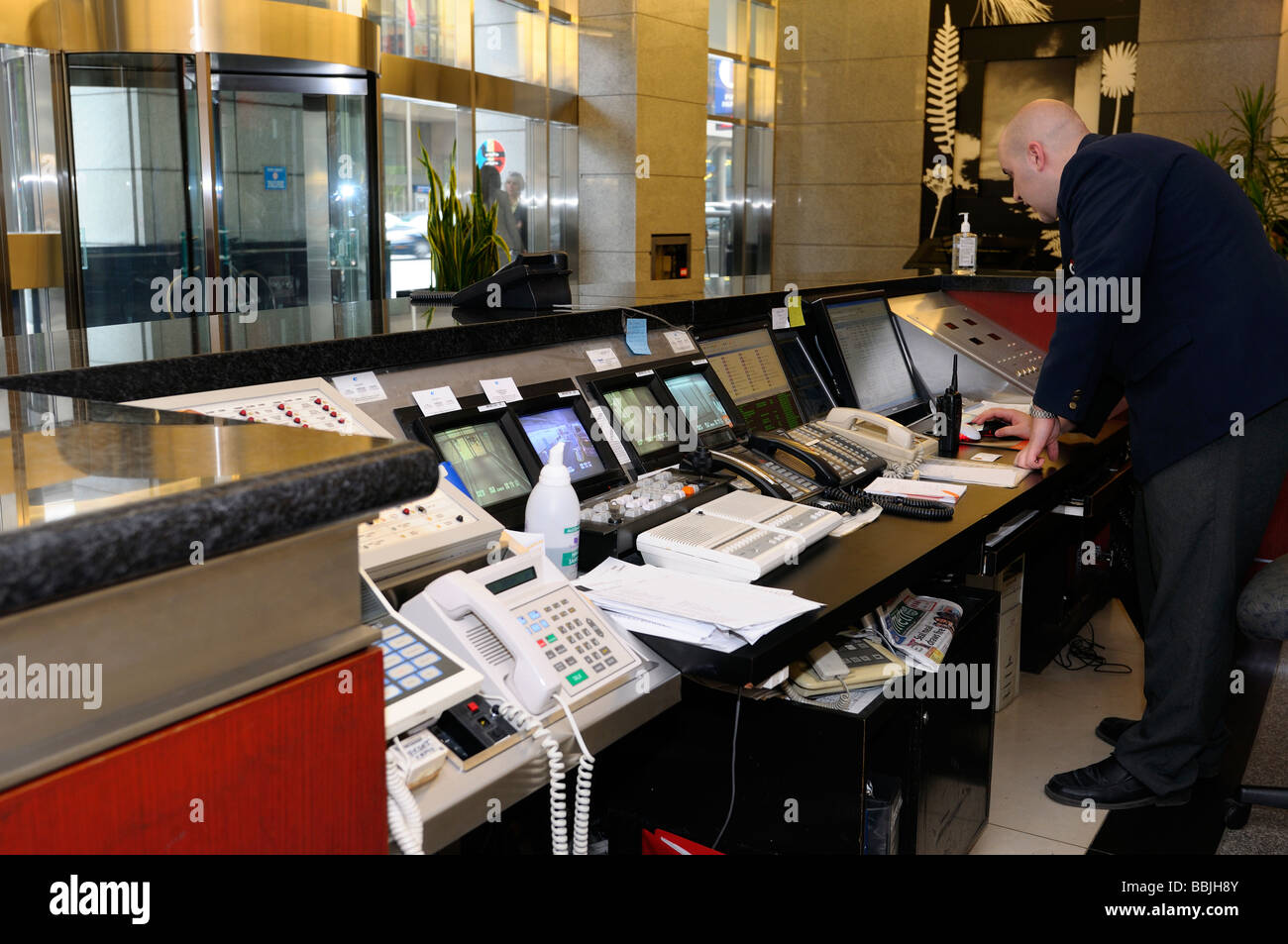 La guardia di sicurezza presso il banco di controllo con i telefoni cellulari e i monitor in highrise edificio per uffici a Toronto Foto Stock