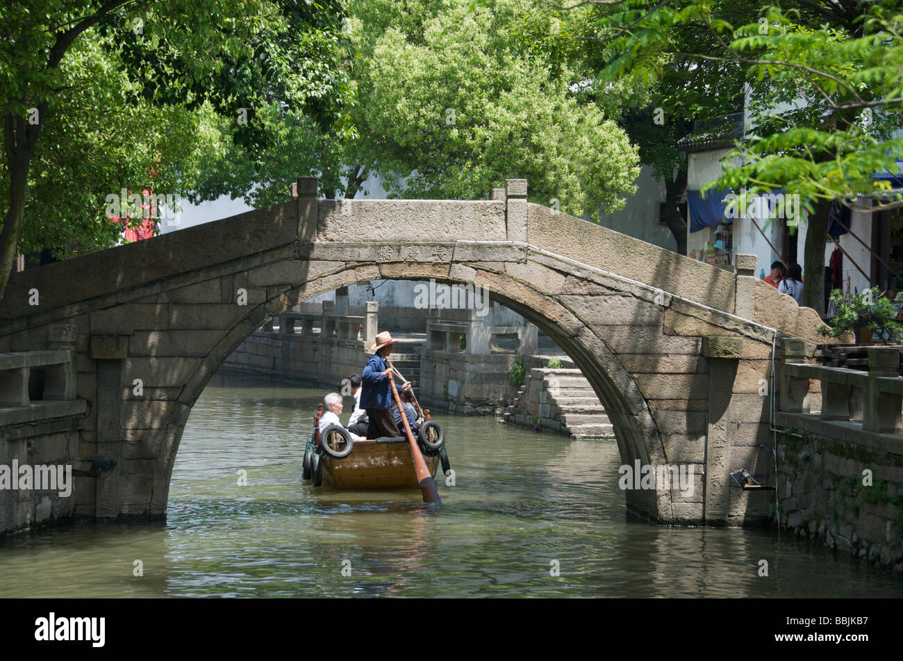 Essendo turistica remando sotto il ponte di pietra sul canal presso l'antica città d'acqua di Tongli Jiansu Cina Foto Stock