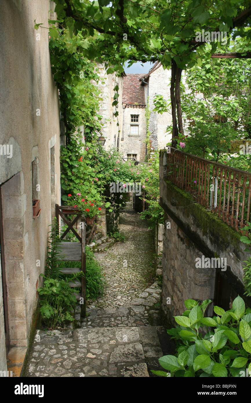 Frondosa strada stretta nel villaggio di Saint-Cirq Lapopie accanto al fiume Lot, Midi Pirenei, Francia Foto Stock
