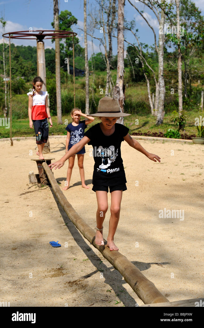 7 anno di età bambino indossando Episteme hat, bilanciamento sulla lunghezza di bambù nel parco giochi. Da Lat, Vietnam Foto Stock