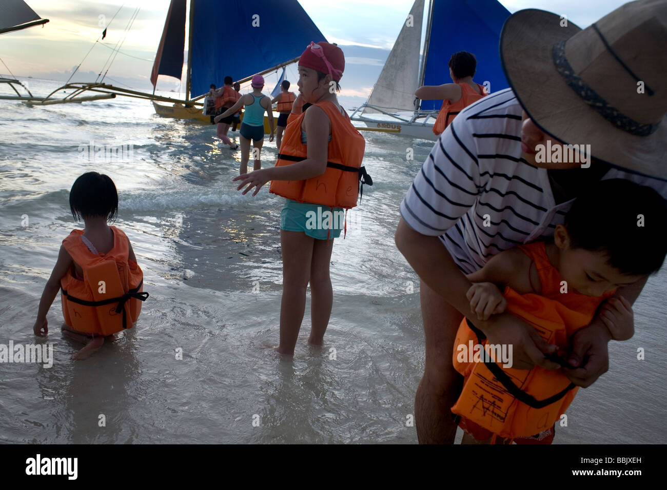 I turisti messo in giubbotti di salvataggio per una serata di vendita al tramonto sull'Isola di Boracay nel Visayas, Filippine Foto Stock