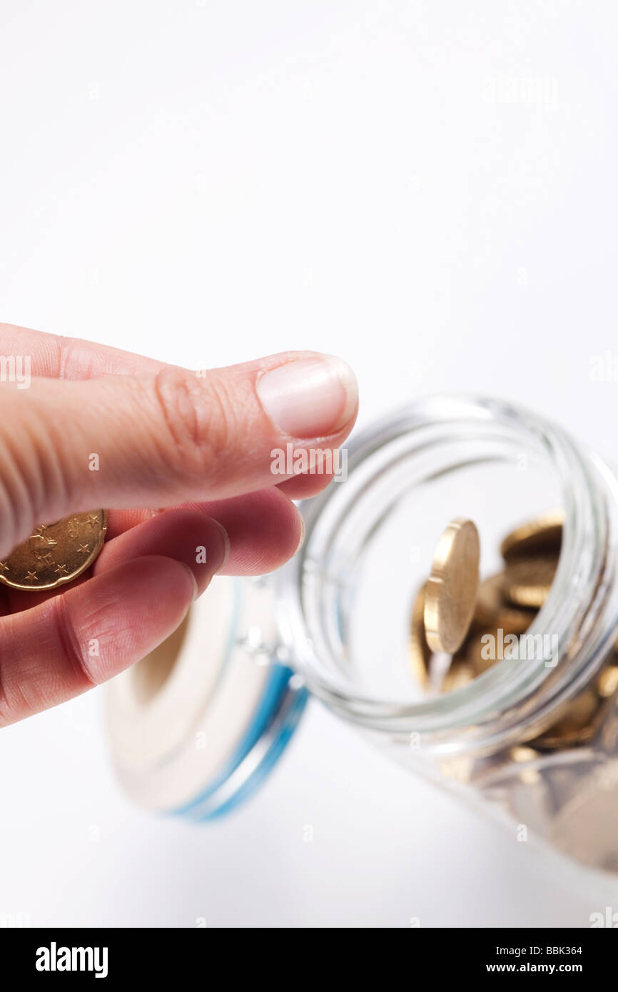 La mano di gettare denaro in un vaso aperto Foto Stock