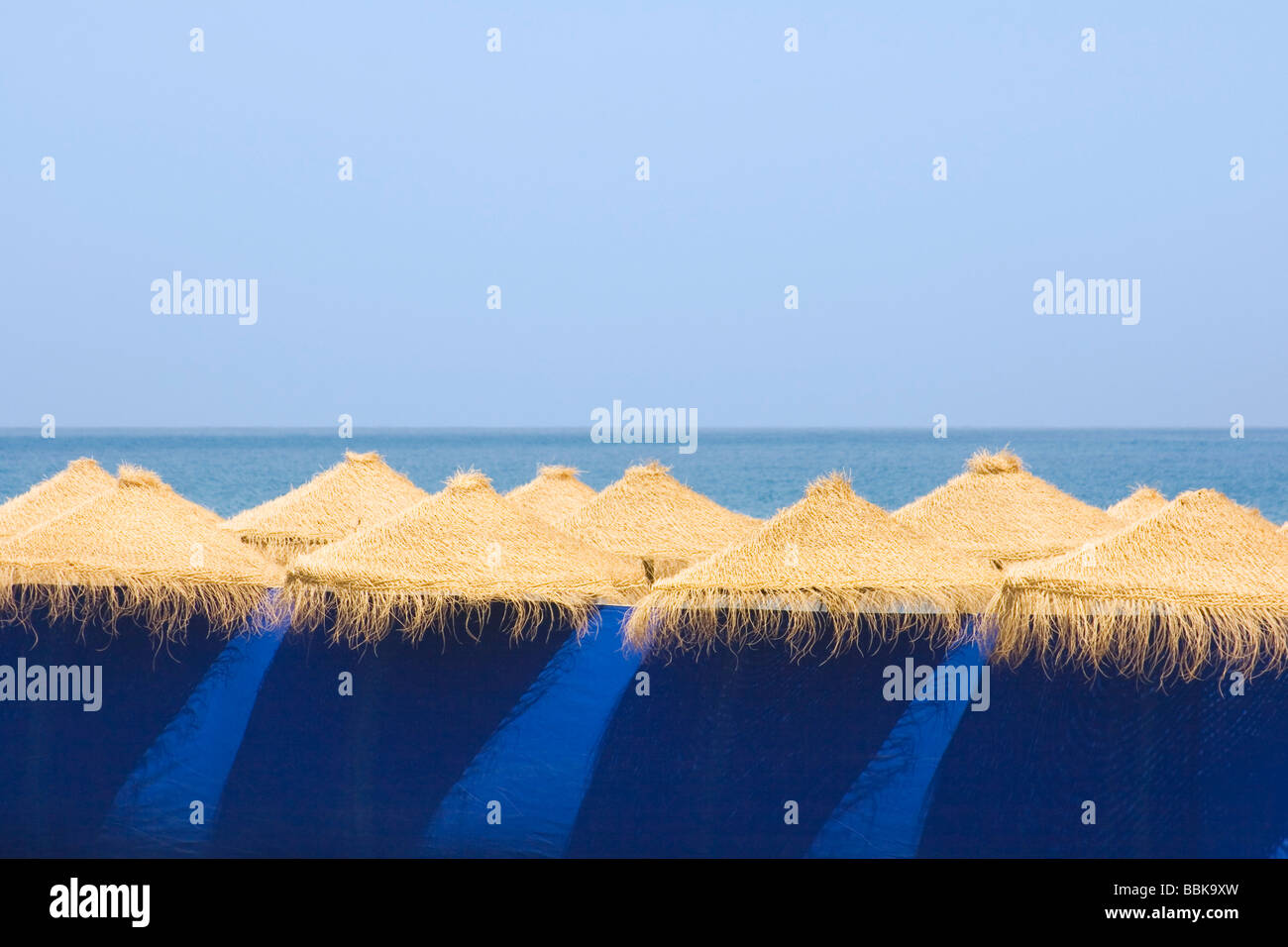 Marbella Malaga Provincia Costa del Sol Spagna fila di ombrelloni da spiaggia dietro il frangivento di blu Foto Stock