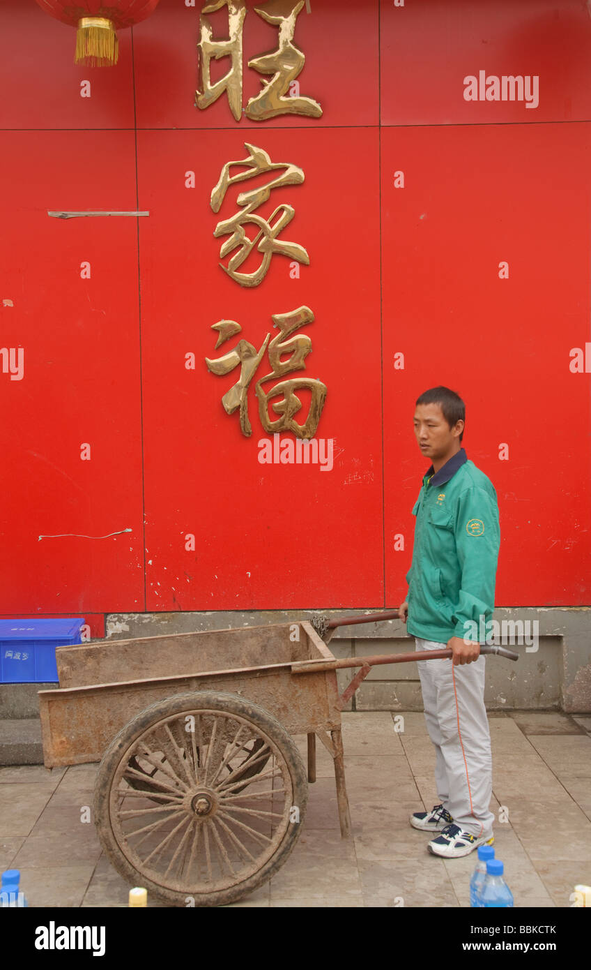 Operaio e il suo carrello nella parte anteriore del segno Yuanyang in Cina Foto Stock