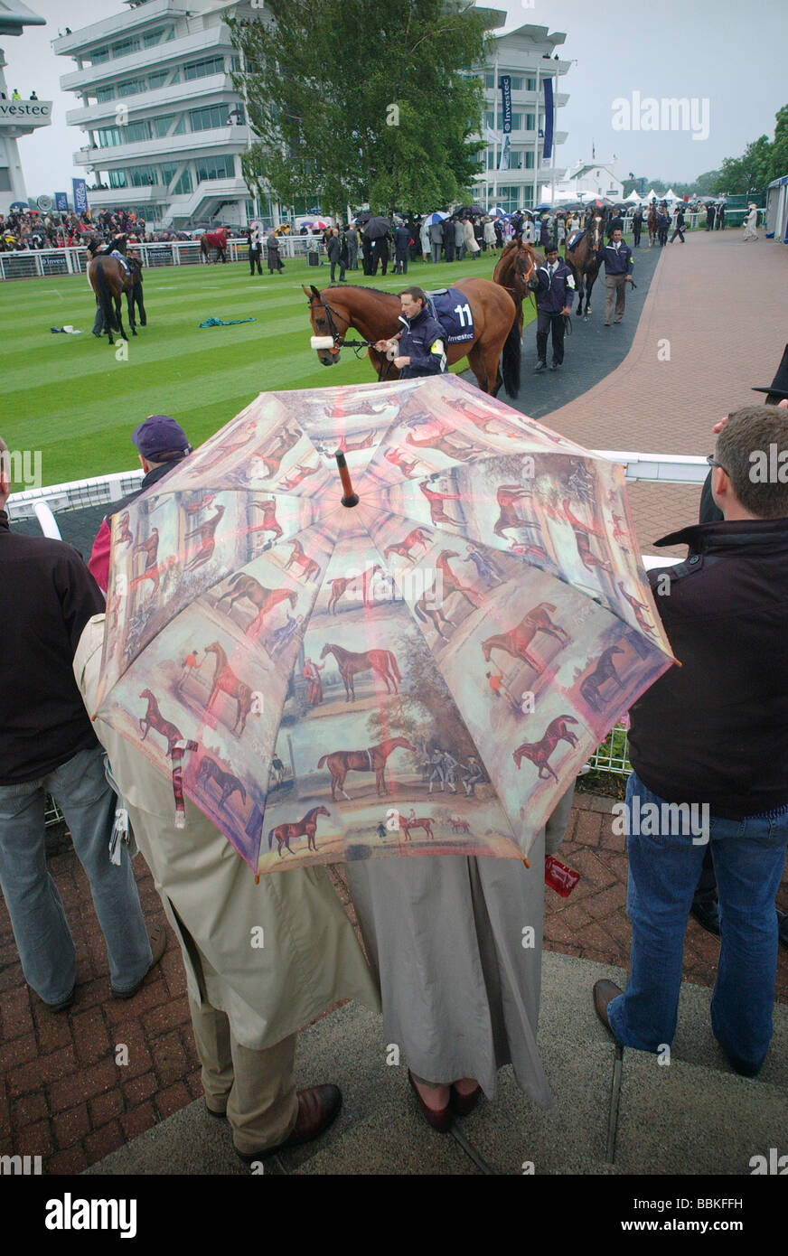 Un giovane sotto un ombrello di grandi dimensioni decorata con i cavalli presso la Epsom gare 2009 Foto Stock