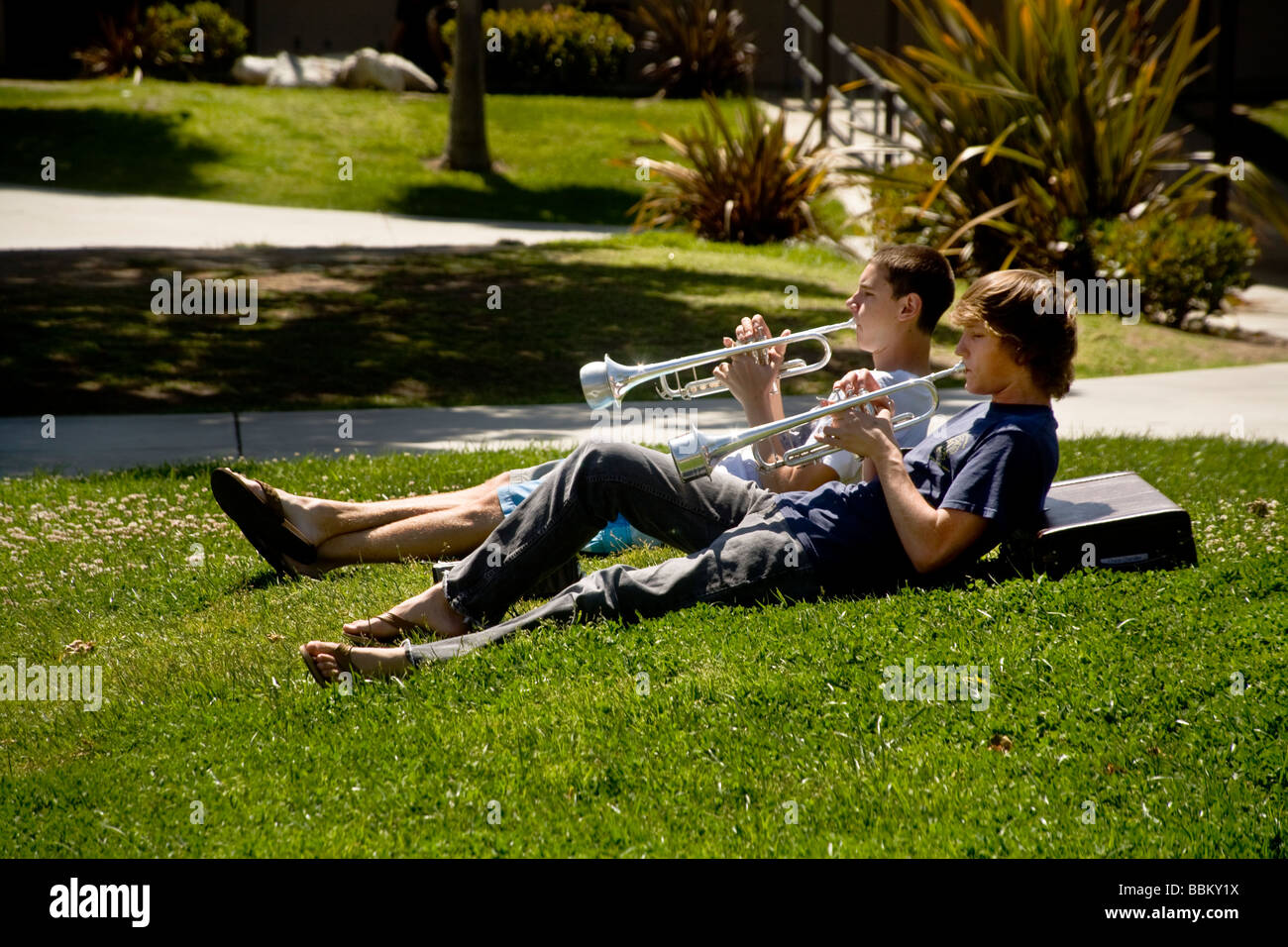 Due Southern California high school i membri della banda di rilassarsi al sole mentre si pratica un duetto sulla loro trombe Foto Stock