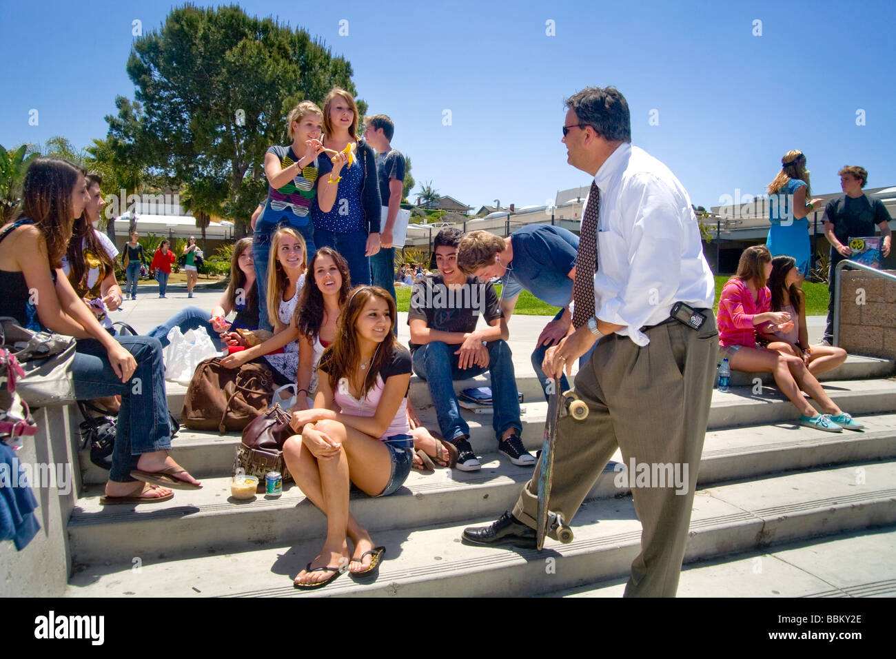 Un Southern California high school principal gode di parlare con i suoi studenti durante la pausa pranzo sul campus nota skateboard Foto Stock