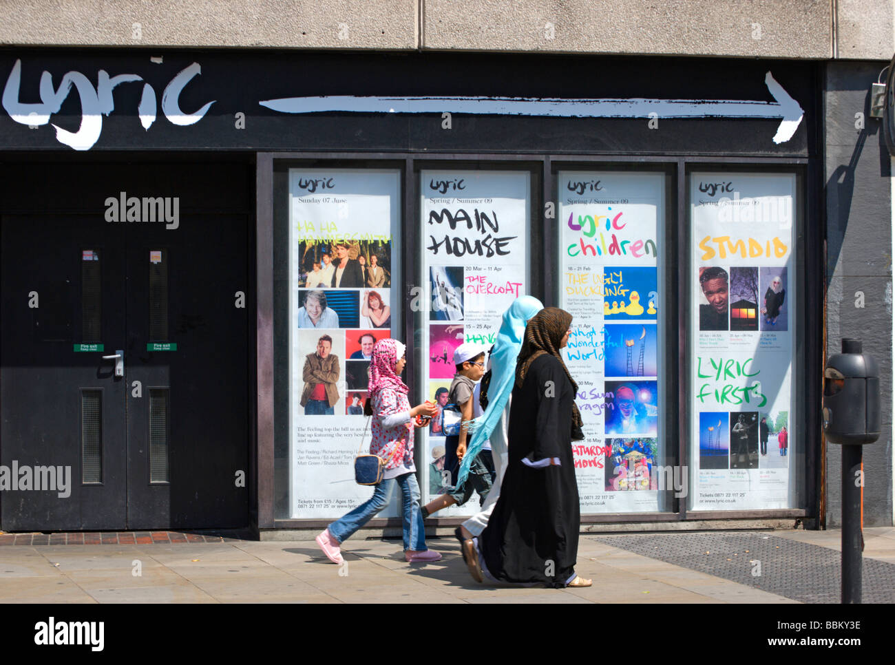 Due donne musulmane e due bambini musulmani a piedi passato il vecchio ingresso del teatro lirico, Hammersmith, ad ovest di Londra - Inghilterra Foto Stock