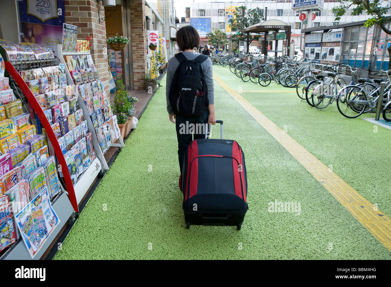 Giovane donna traveler valigia tira verso la stazione di Oita, Oita, Giappone Foto Stock