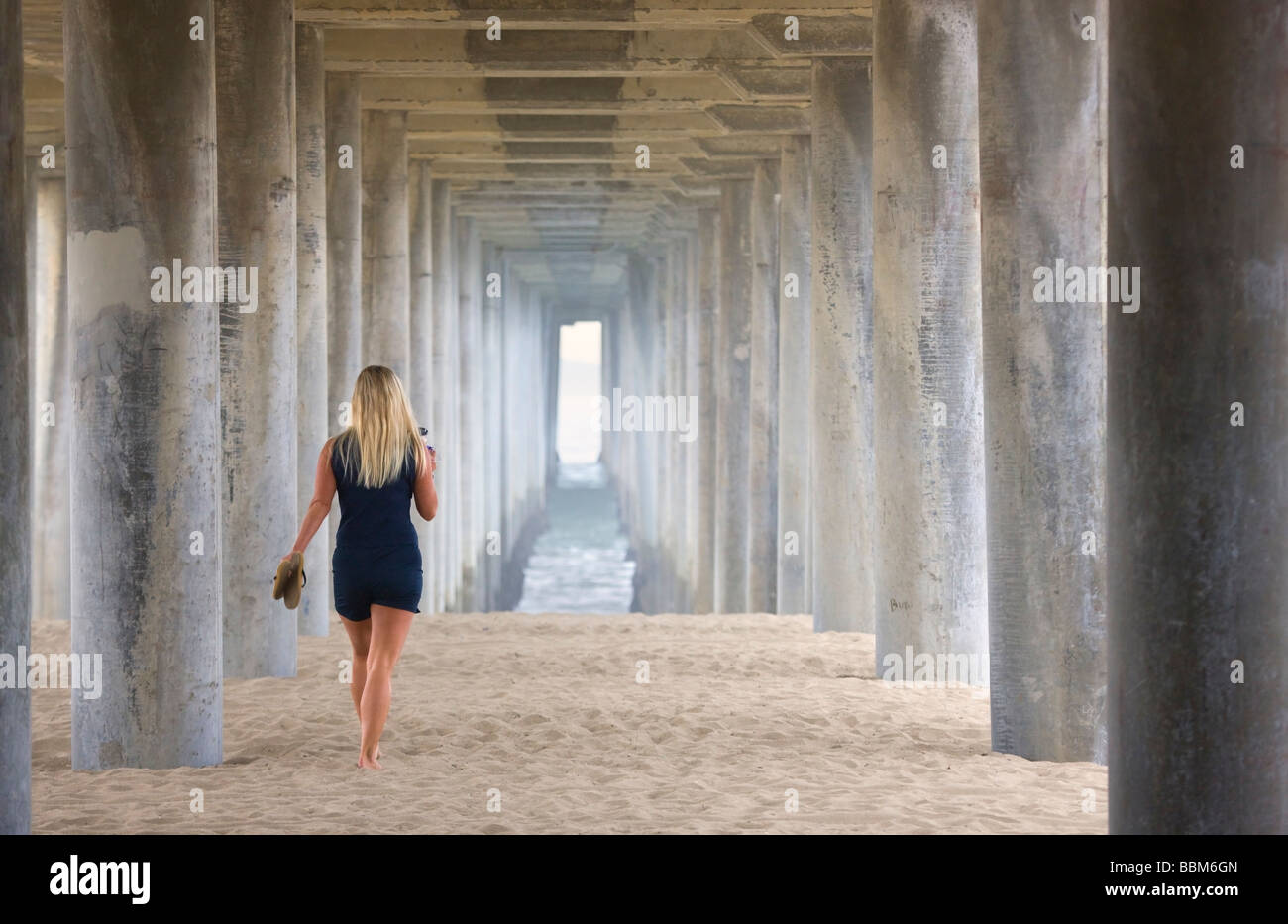 Donna camminare sotto il molo Huntington Beach Orange County in California Foto Stock