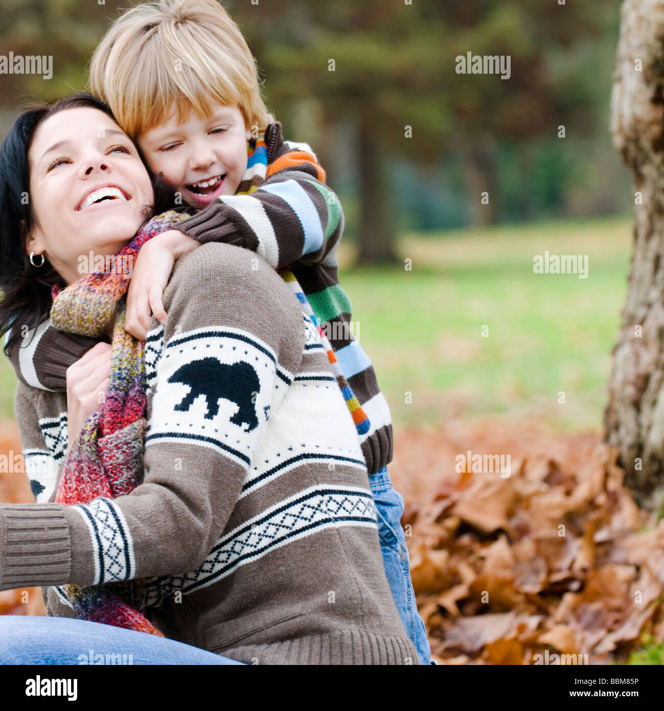 Ragazzo giovane madre abbraccia da dietro, all'aperto in autunno, Vancouver, British Columbia Foto Stock