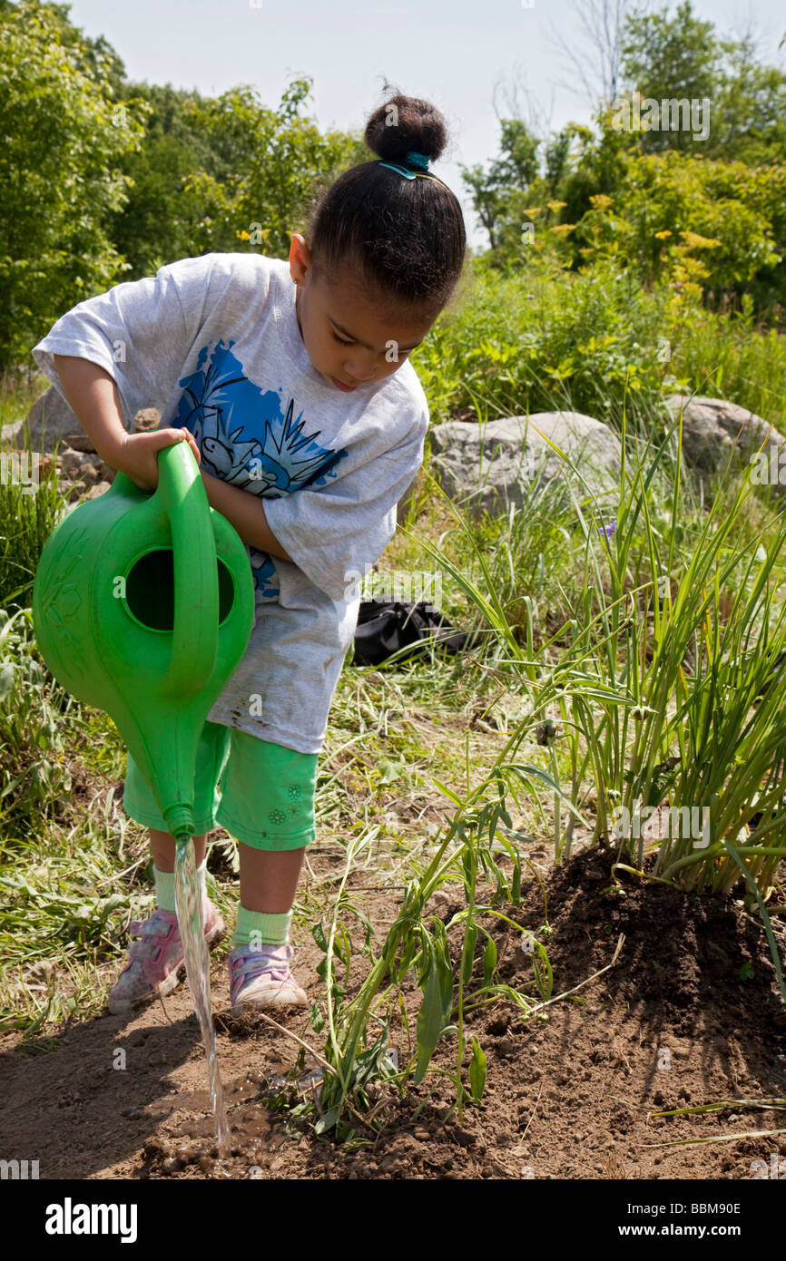 Detroit Michigan un giovane bambino acque piante piantate da volontari in Rouge Park come parte di un parco cleanup Foto Stock