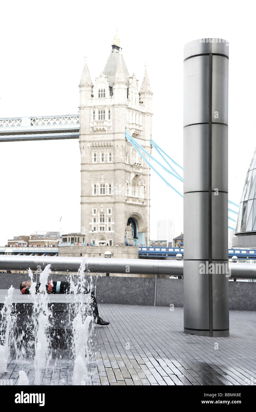 Uomo disteso lungo il Tamigi, con il Tower Bridge in background Foto Stock