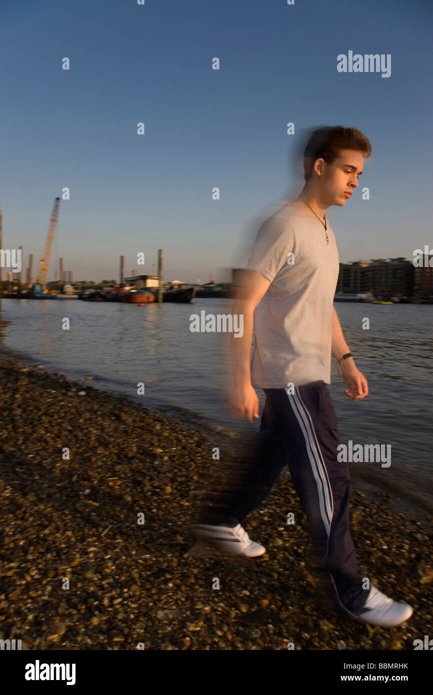 Un ragazzo adolescente camminando lungo il Tamigi a bassa marea Foto Stock