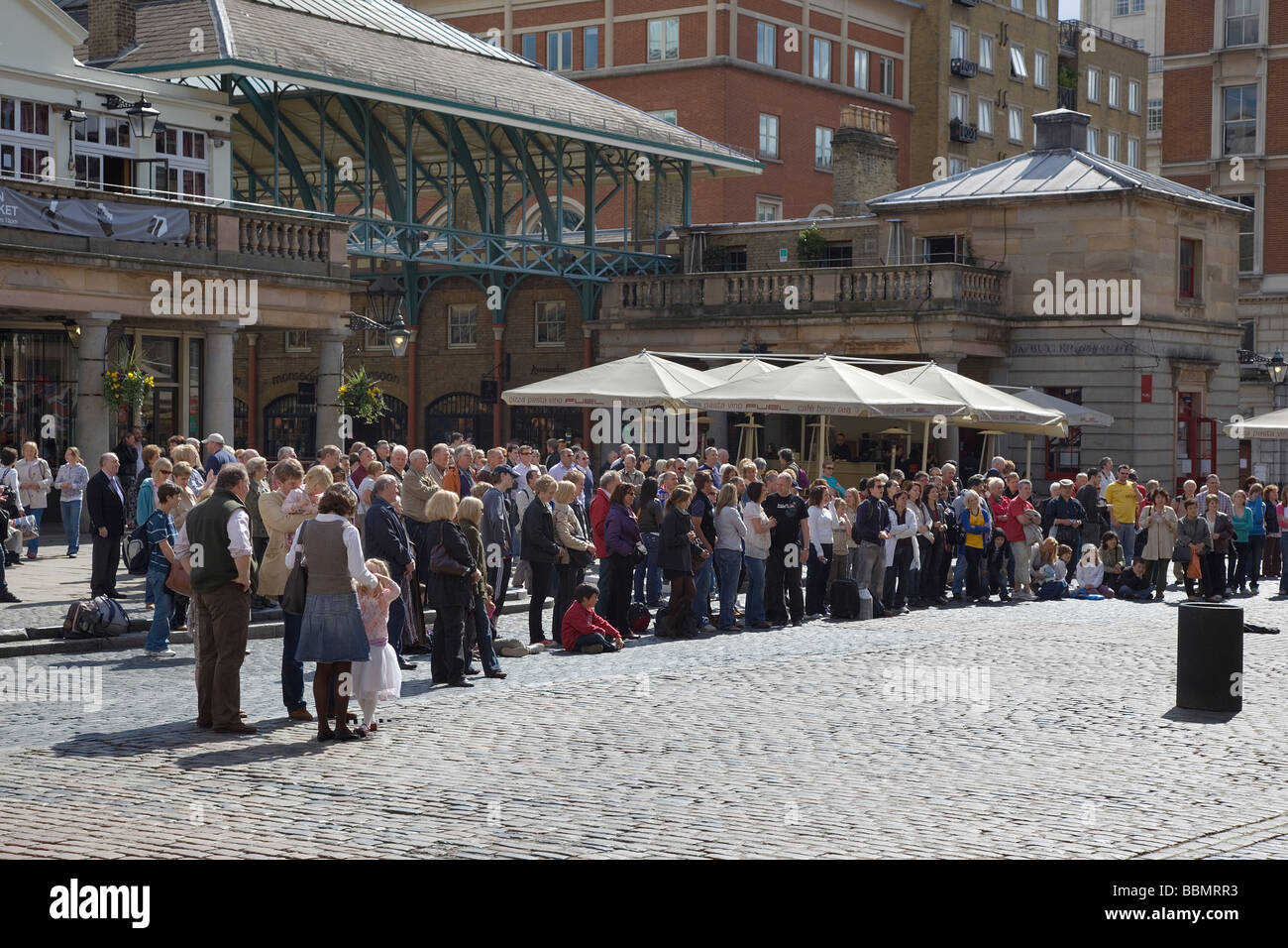 Una piccola folla guarda a un esecutore al Covent Garden di Londra Foto Stock